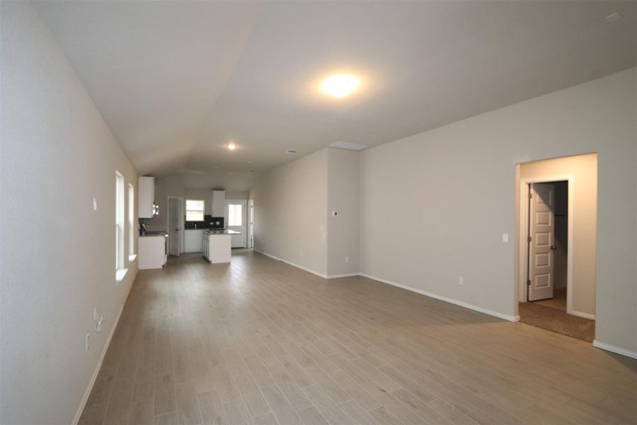 Unfurnished living room with light hardwood / wood-style flooring and vaulted ceiling