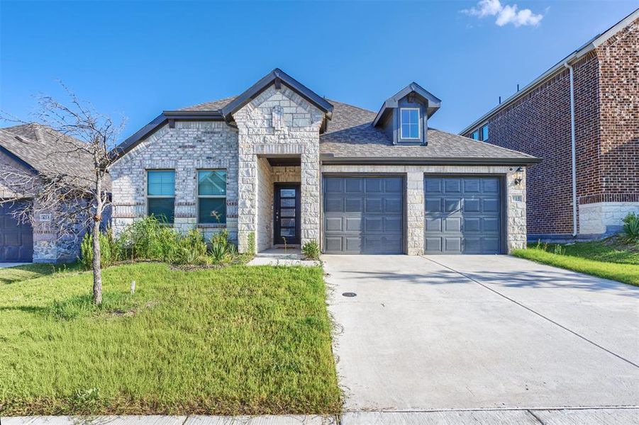 View of front of house with stone siding, an attached garage, driveway, a shingled roof, and a front yard View of front of house with stone siding, an attached garage, driveway, a shingled roof, and a front yard
