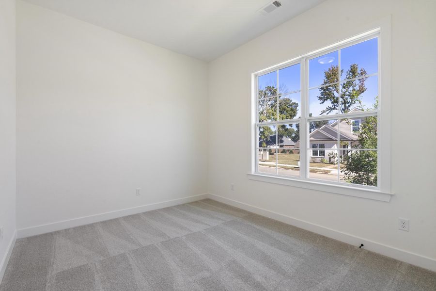 Neutral-toned interior space featuring wall-to-wall carpeting and a large multi-pane window with white trim Neutral-toned interior space featuring wall-to-wall carpeting and a large multi-pane window with white trim