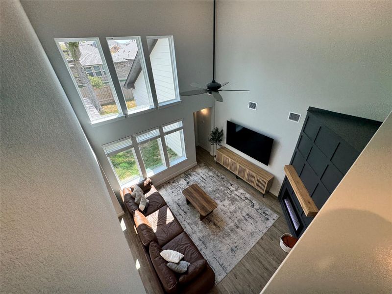 Living area with a high ceiling, wood finished floors, a textured wall, and a ceiling fan