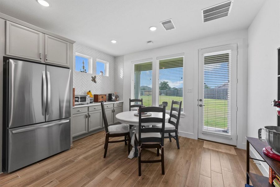 The dining area is filled with natural light from large windows and a glass-paned door that leads to the backyard. This bright and airy space is ideal for enjoying meals with family and friends.