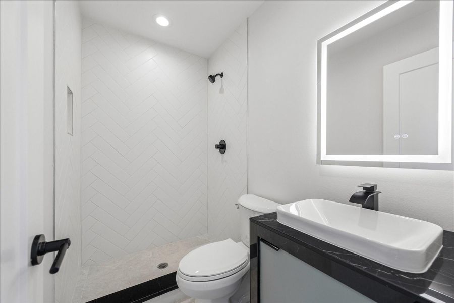 Contemporary bathroom featuring a spacious walk-in shower with full-height herringbone tile, matte black fixtures, and a sleek floating vanity. Contemporary bathroom featuring a spacious walk-in shower with full-height herringbone tile, matte black fixtures, and a sleek floating vanity.