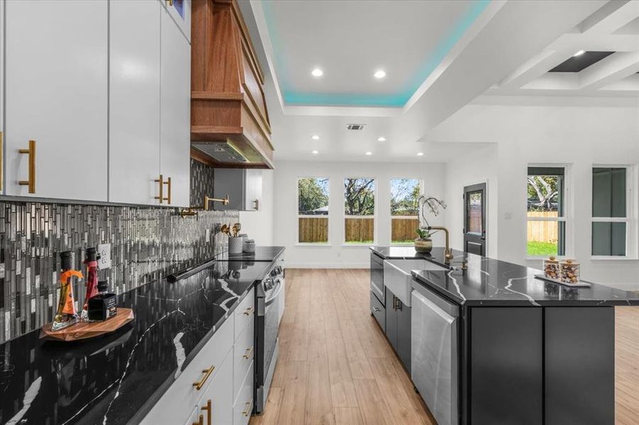 Kitchen with light wood-style flooring, dark cabinetry, white cabinets, appliances with stainless steel finishes, and recessed lighting