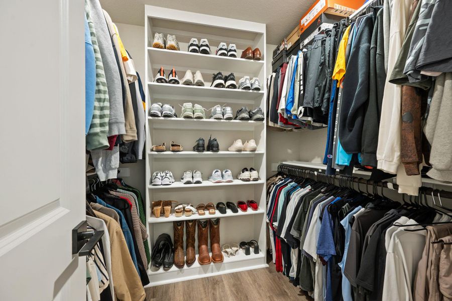 A spacious walk-in closet includes custom shelving and durable wood-look flooring. A spacious walk-in closet includes custom shelving and durable wood-look flooring.
