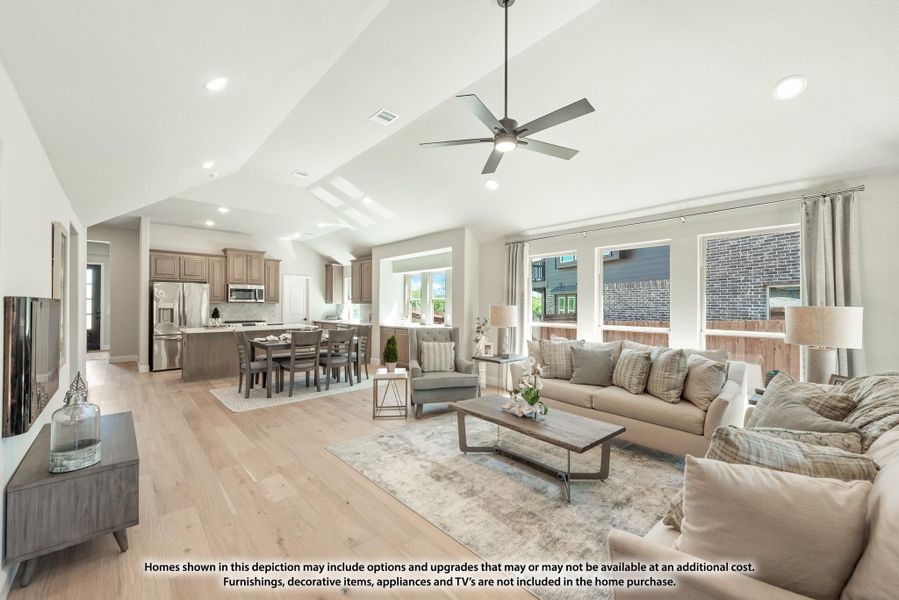 Open-concept living room with vaulted ceiling, ceiling fan, and hardwood floors, open to dining area and kitchen beyond. Open-concept living room with vaulted ceiling, ceiling fan, and hardwood floors, open to dining area and kitchen beyond.