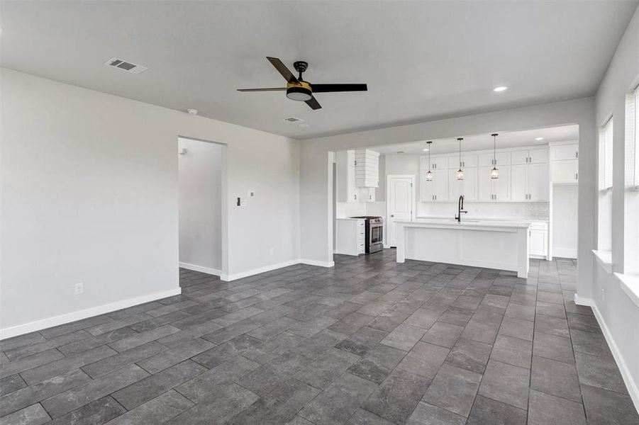 Unfurnished living room featuring a sink, ceiling fan, recessed lighting, and baseboards