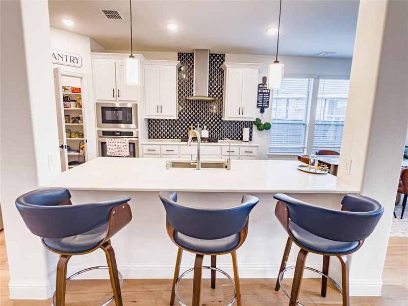 Kitchen featuring white cabinetry, oven, a kitchen breakfast bar, and light wood finished floors