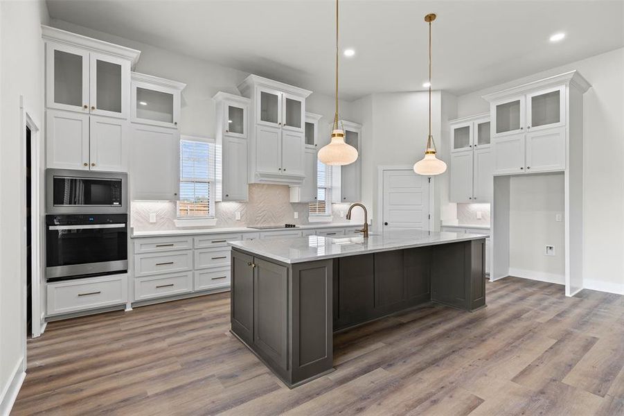 Kitchen with glass insert cabinets, decorative backsplash, white cabinetry, appliances with stainless steel finishes, and recessed lighting Kitchen with glass insert cabinets, decorative backsplash, white cabinetry, appliances with stainless steel finishes, and recessed lighting