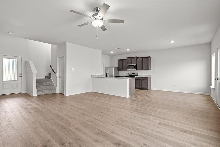 Unfurnished living room featuring plenty of natural light, stairway, light wood-style flooring, ceiling fan, and recessed lighting Unfurnished living room featuring plenty of natural light, stairway, light wood-style flooring, ceiling fan, and recessed lighting
