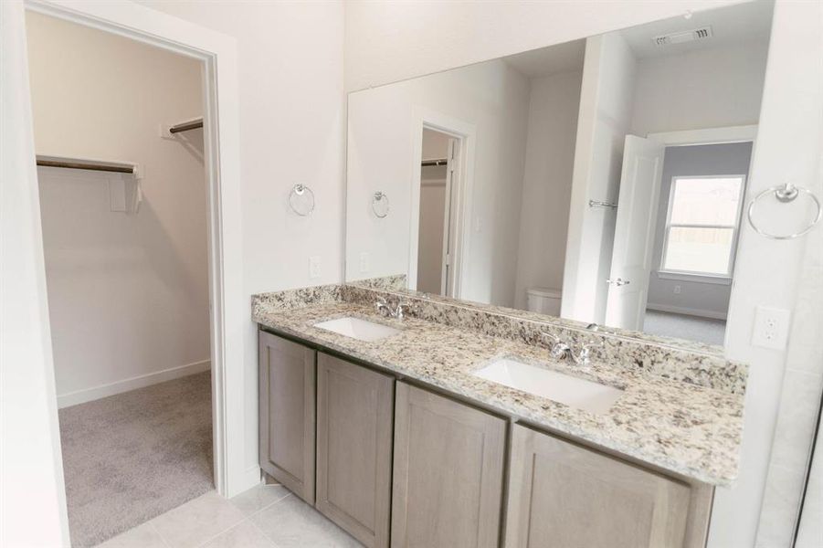 Bathroom featuring toilet, tile patterned flooring, and double vanity