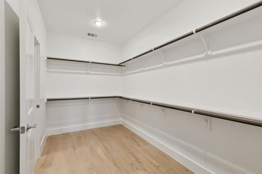 Spacious closet with light wood-style flooring Spacious closet with light wood-style flooring