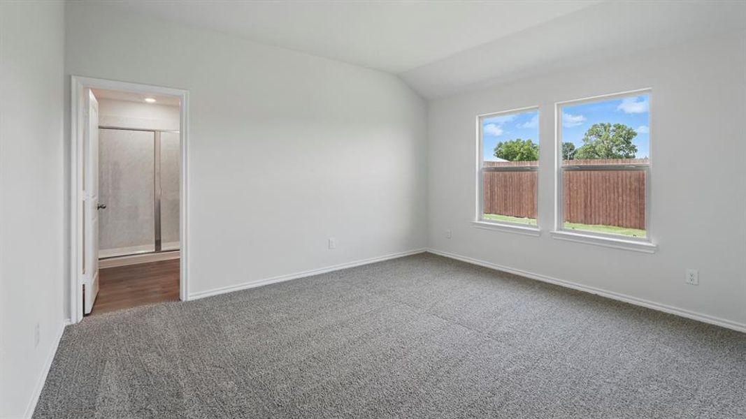 Carpeted empty room with vaulted ceiling and baseboards