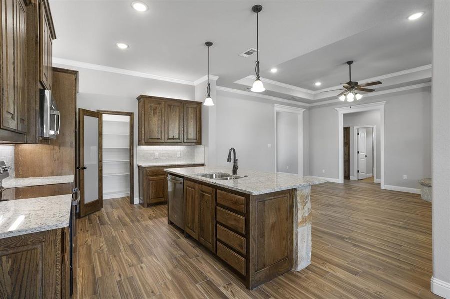 Kitchen featuring sink, dark hardwood / wood-style flooring, backsplash, and an island with sink