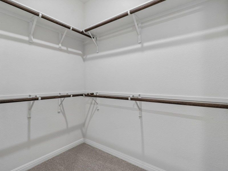 Multi-level hanging rods provide organized storage solutions within this neutral closet space.