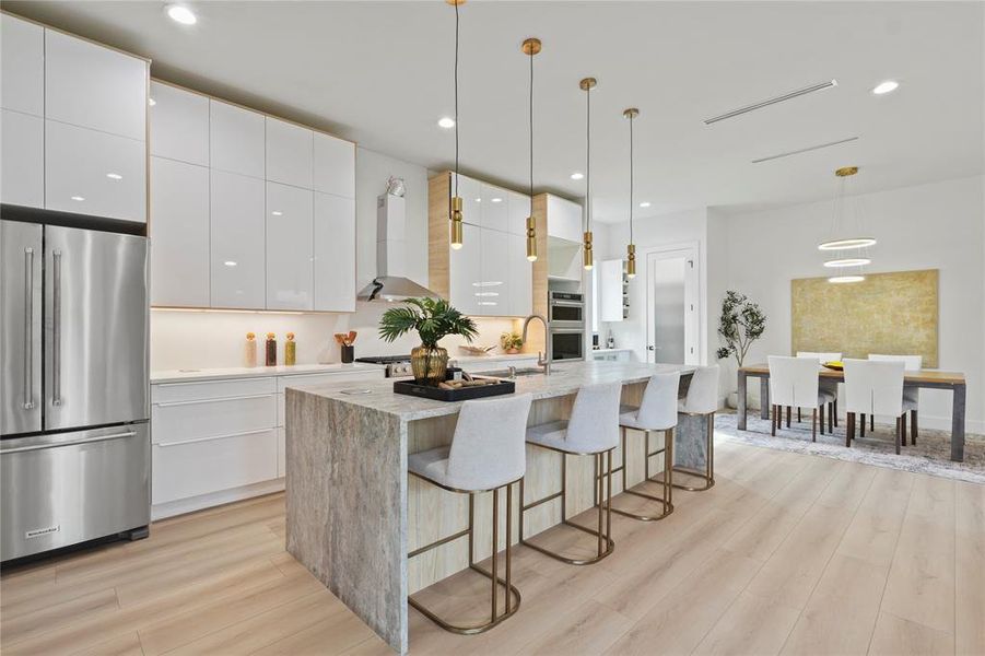 Kitchen featuring modern cabinets, stainless steel appliances, hanging light fixtures, white cabinetry, and light stone counters Kitchen featuring modern cabinets, stainless steel appliances, hanging light fixtures, white cabinetry, and light stone counters