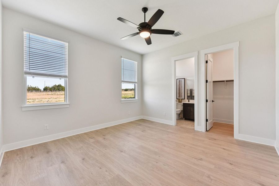 Unfurnished bedroom featuring a walk in closet, light wood finished floors, and ceiling fan