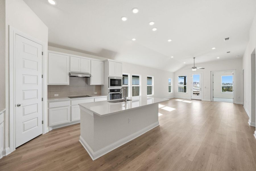 Kitchen with decorative backsplash, recessed lighting, white cabinetry, a center island with sink, and vaulted ceiling Kitchen with decorative backsplash, recessed lighting, white cabinetry, a center island with sink, and vaulted ceiling