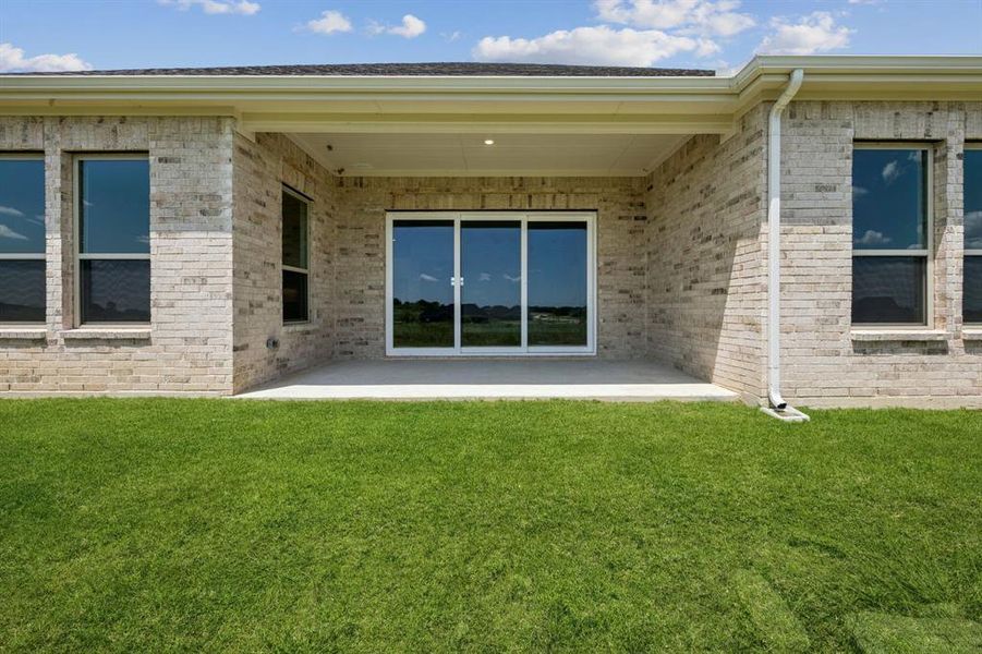 Rear view of property featuring a patio, brick siding, and a lawn