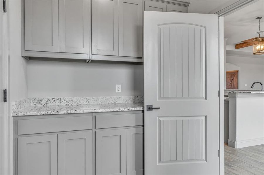 Kitchen featuring light hardwood / wood-style flooring, gray cabinetry, light stone countertops, and sink