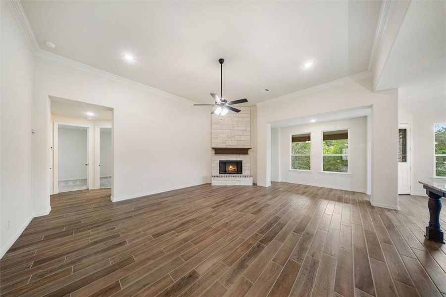 Unfurnished living room featuring ceiling fan, a fireplace, ornamental molding, recessed lighting, and dark wood finished floors
