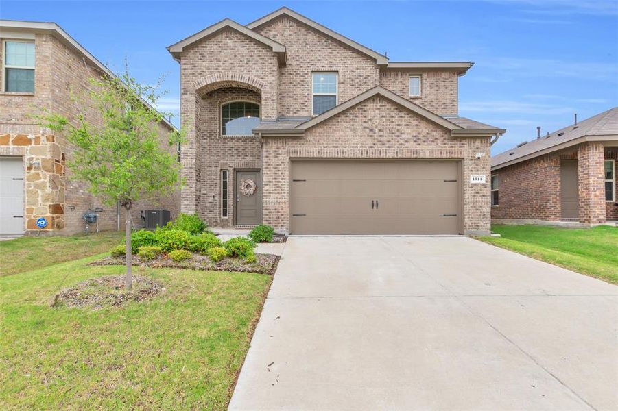Traditional-style home featuring brick siding, a front yard, driveway, and an attached garage Traditional-style home featuring brick siding, a front yard, driveway, and an attached garage