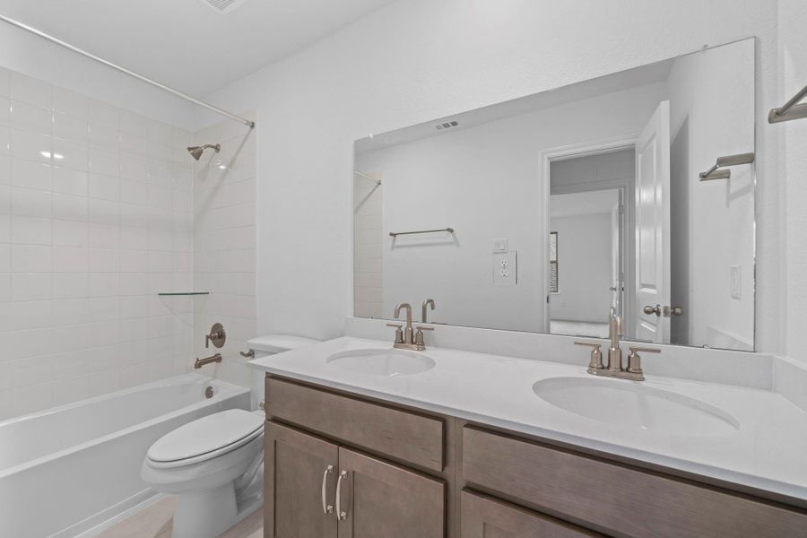 The secondary bath features tile flooring, white cabinetry and light countertops and a shower/tub combo. Perfect for accommodating any visiting family and friends.
