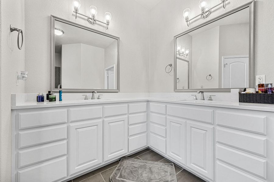 Dual vanity offers abundant storage with pristine white cabinetry and sleek countertops. Dual vanity offers abundant storage with pristine white cabinetry and sleek countertops.