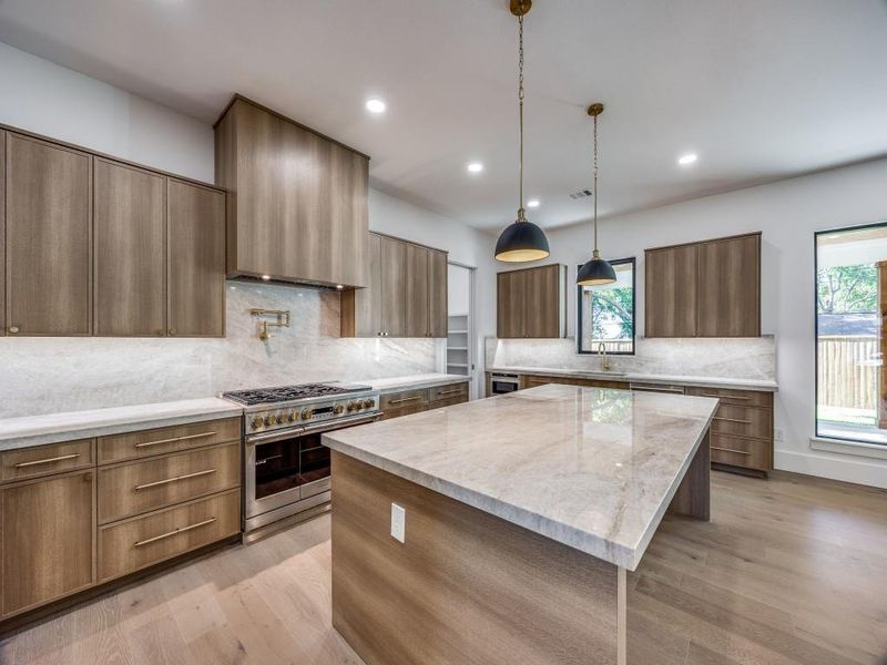 Kitchen featuring light wood-type flooring, high end stainless steel range oven, a wealth of natural light, and a kitchen island