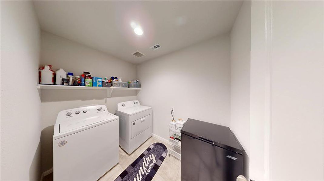 Dedicated utility room featuring light-toned walls, overhead lighting, and built-in shelving