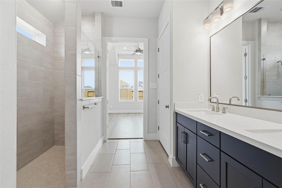 Retreat to a private, spa-like primary bathroom designed for relaxation and convenience. A generous double vanity with modern cabinetry offers ample space for two people.