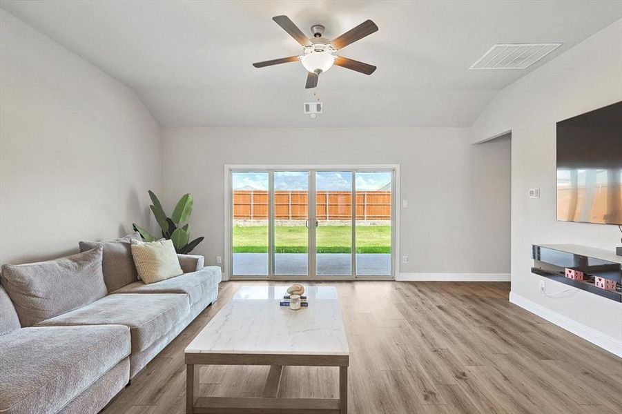 Living room with wood-type flooring, ceiling fan, and vaulted ceiling