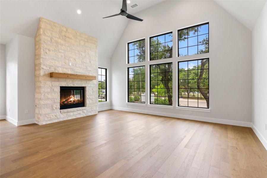 A striking stone fireplace anchors a luminous living area with towering windows that frame natural outdoor views.
