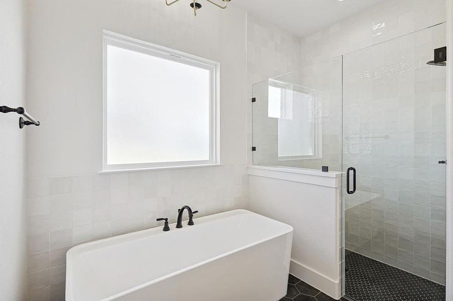 Primary Bathroom with tile patterned floors, shower with separate bathtub, and tile walls