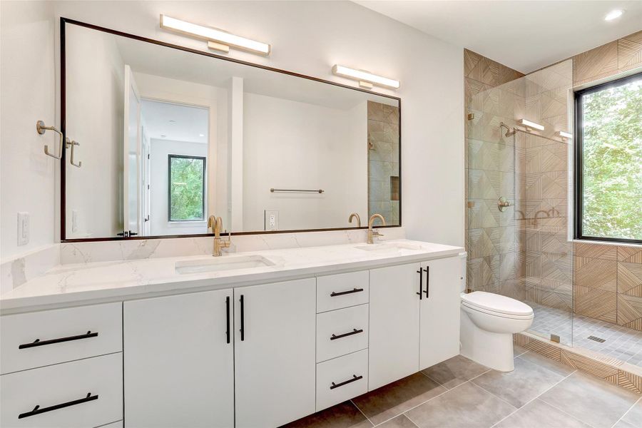 Bathroom with healthy amount of natural light, double vanity, tiled shower, and tile patterned floors Bathroom with healthy amount of natural light, double vanity, tiled shower, and tile patterned floors