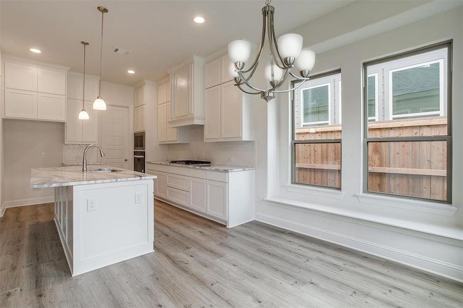 Kitchen with white cabinets, decorative backsplash, light hardwood / wood-style flooring, and sink