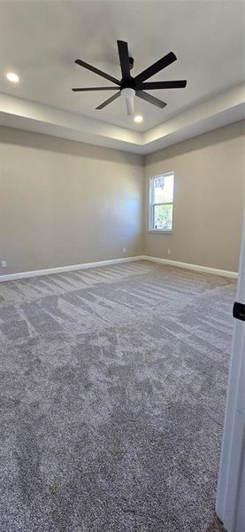 Unfurnished room with dark colored carpet, ceiling fan, a tray ceiling, and recessed lighting Unfurnished room with dark colored carpet, ceiling fan, a tray ceiling, and recessed lighting