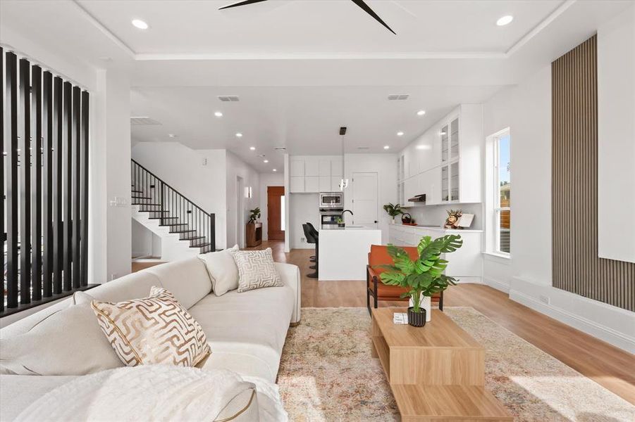 Living room with recessed lighting, light wood finished floors, a ceiling fan, and stairway Living room with recessed lighting, light wood finished floors, a ceiling fan, and stairway