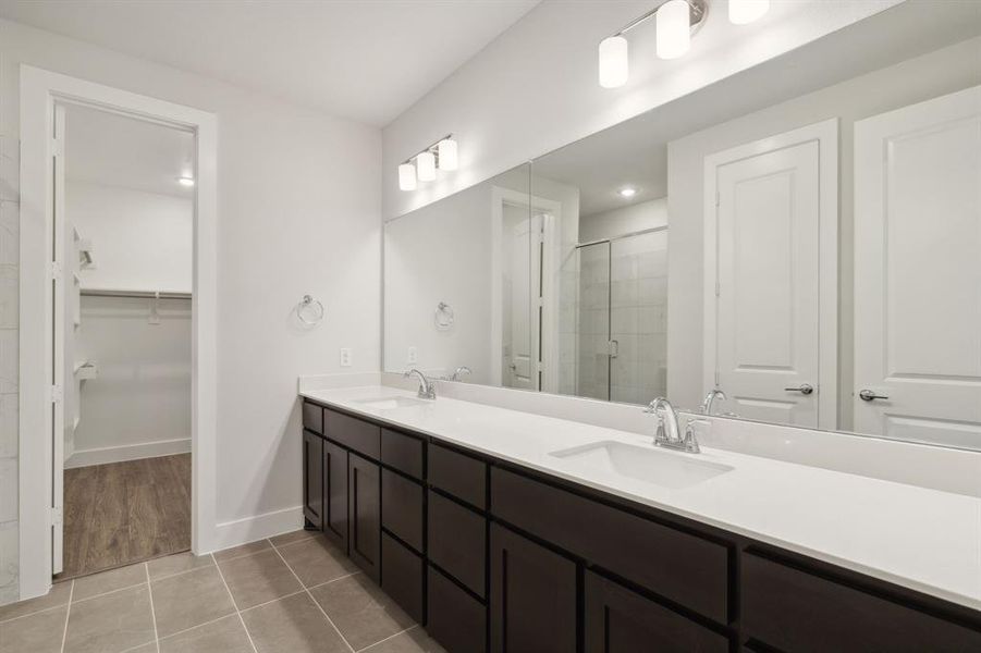 Full primary bath with double vanity, a sink, a large walk-in shower, and tile patterned floors