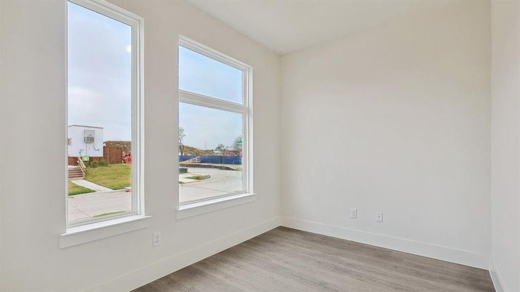 Bright interior space featuring multiple windows, wood-finish flooring, white baseboards, and neutral wall finishes