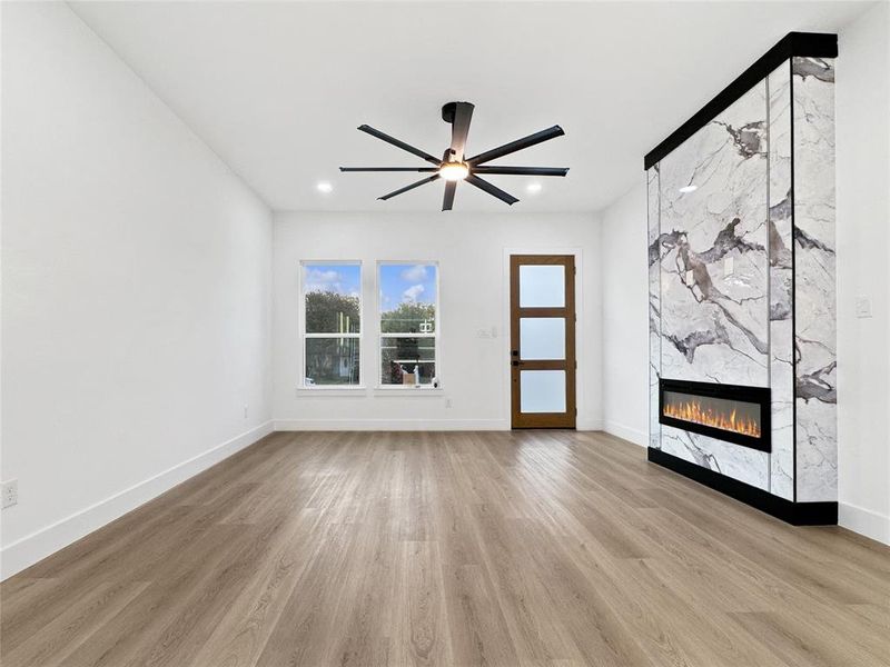 Unfurnished living room with a fireplace, light wood-style flooring, and a ceiling fan