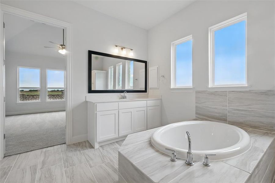 Bathroom with vanity, ceiling fan, and a bath