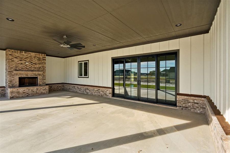 View of patio featuring an outdoor brick fireplace and ceiling fan