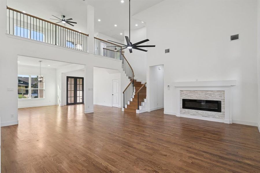 Unfurnished living room featuring recessed lighting, a stone fireplace, dark real-wood finished floors, a ceiling fan, and stairs