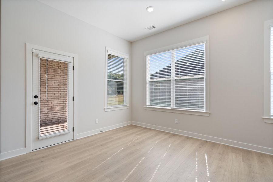Light wood-finish flooring, white walls, multiple windows with blinds, recessed ceiling lighting, and a glass-paneled door Light wood-finish flooring, white walls, multiple windows with blinds, recessed ceiling lighting, and a glass-paneled door