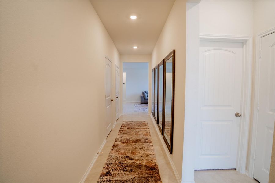 Hallway with light-colored walls, recessed ceiling lighting, and tile flooring Hallway with light-colored walls, recessed ceiling lighting, and tile flooring