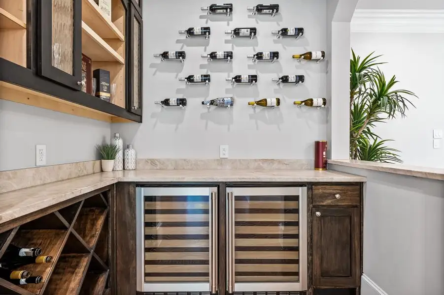 Bar with dark brown cabinetry, wine cooler, and crown molding