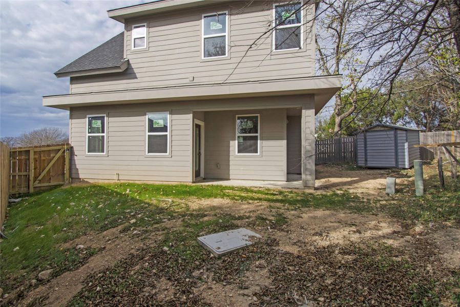Back of house with a patio area, a fenced backyard, a storage unit, a gate, and a shingled roof