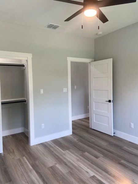 A well-lit bedroom features sturdy laminate flooring and an open closet, ready for personalization. A well-lit bedroom features sturdy laminate flooring and an open closet, ready for personalization.