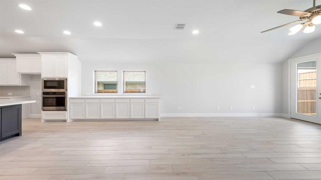 Unfurnished living room with light wood-type flooring, lofted ceiling, and ceiling fan