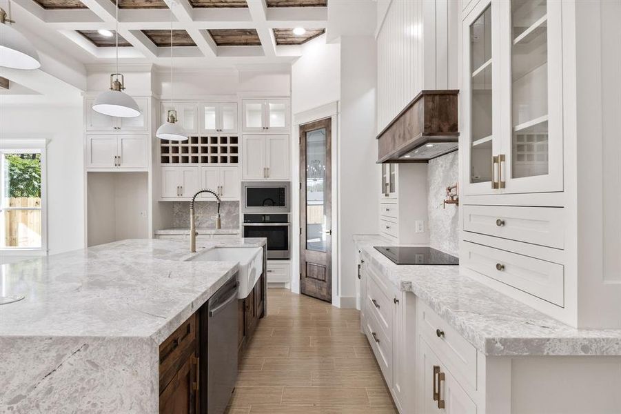 Kitchen featuring glass insert cabinets, white cabinets, light stone counters, stainless steel appliances, and decorative light fixtures